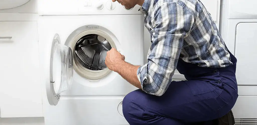Handyman inspecting a dryer drum and internal parts for repair in Pittsburgh, PA