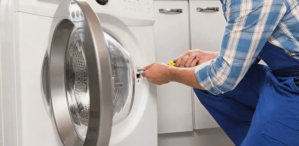 Handyman repairing a clothes dryer and checking electrical connections in Pittsburgh, PA