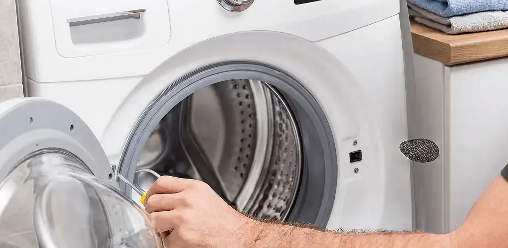 Handyman repairing a front-load washing machine and inspecting the drum in Pittsburgh, PA