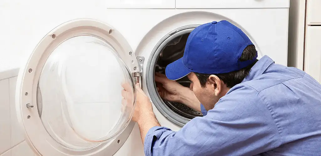 Washing machine repair handyman inspecting a front-load washer drum in Pittsburgh, PA